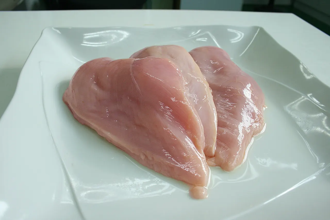 Boneless raw chicken breast slices on a cutting board