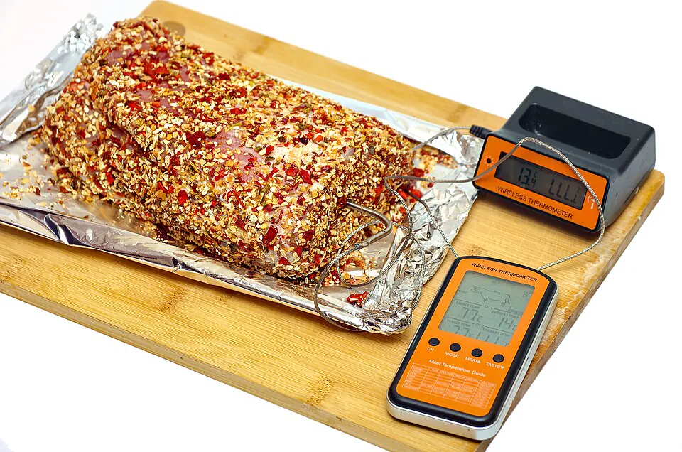 Digital probe thermometers beside a seasoned roast on a cutting board